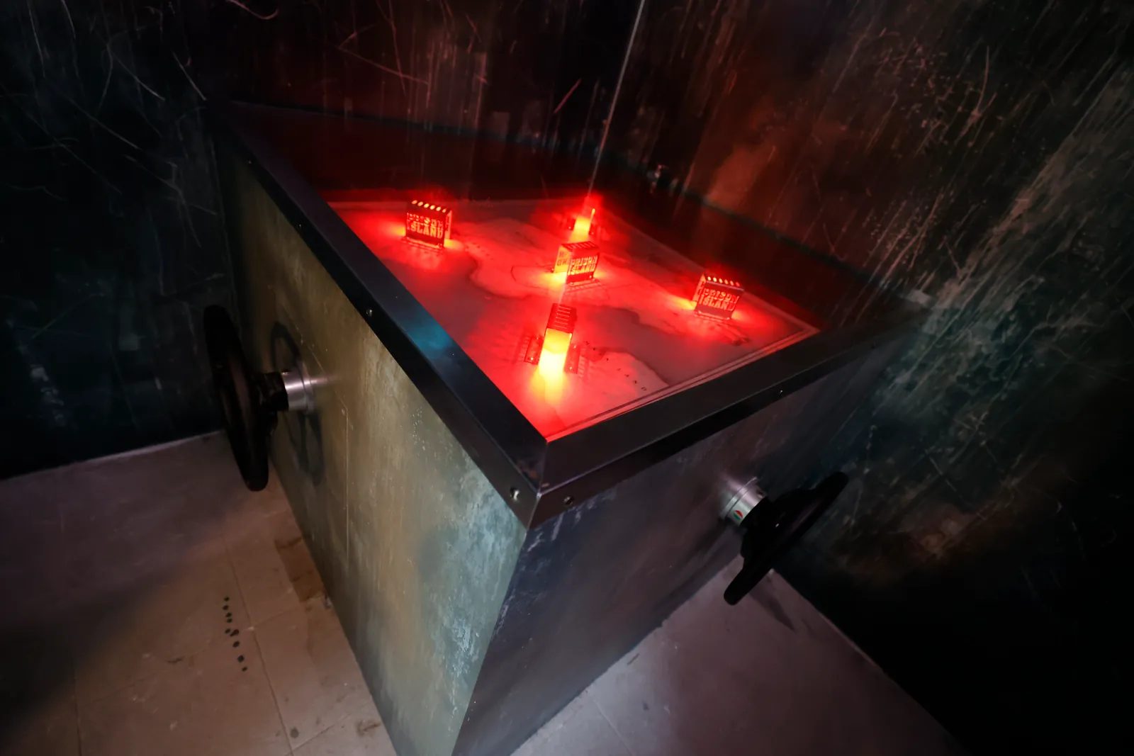 Une cellule sombre avec un bac rouge lumineux et des cibles à atteindre